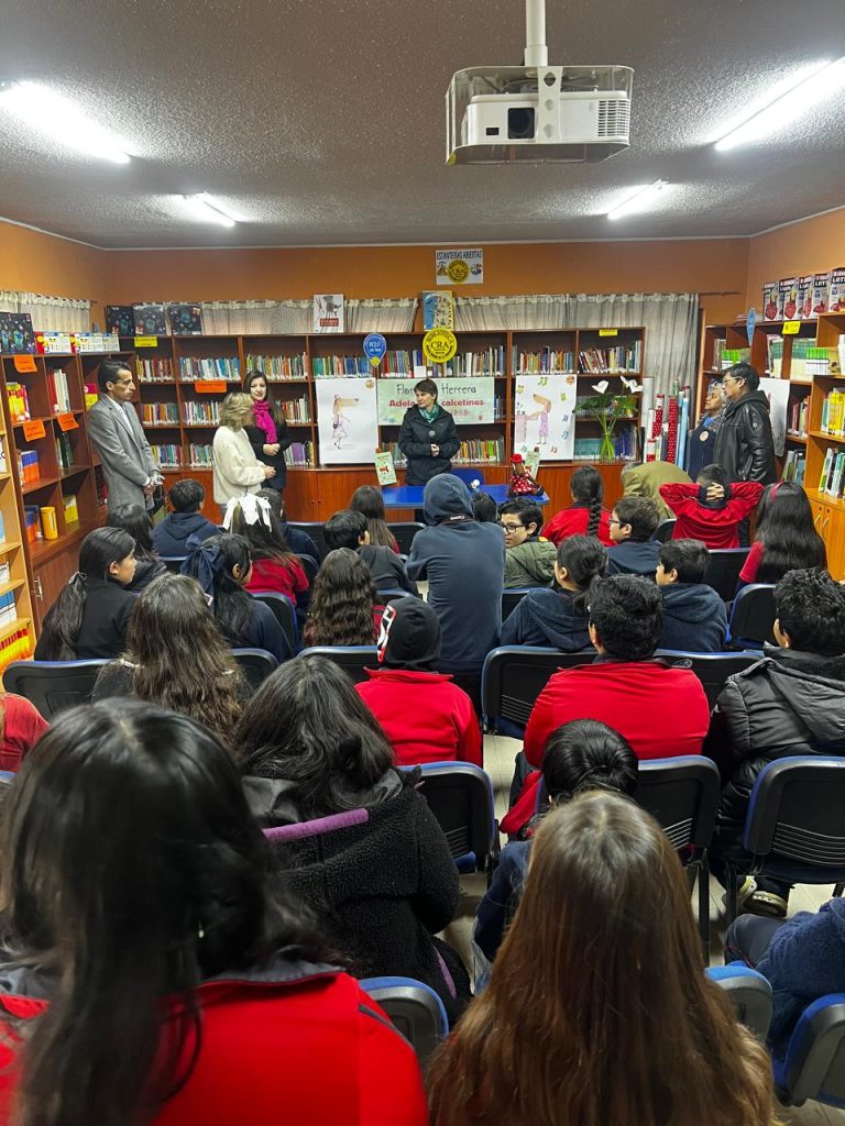 Fotografía de un evento donde Florencia Herrera presenta el libro Adela y los Calcetines perdidos, donde se ve a gente escuchándola y ella está parada al frente.